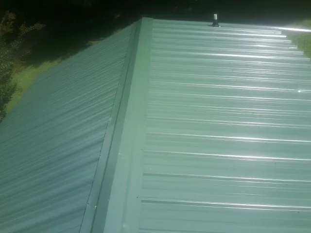 New green metal panels meeting at the ridge of a roof — Flat Roof Repair work by our crew in Wapato