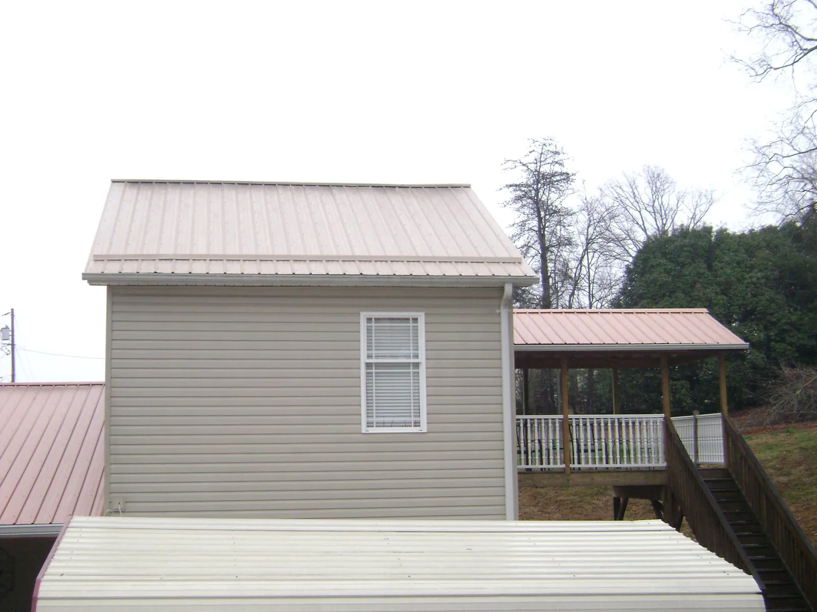 Tan metal roofs on a two story addition and attached porch, from a Roof Replacement job in Wapato
