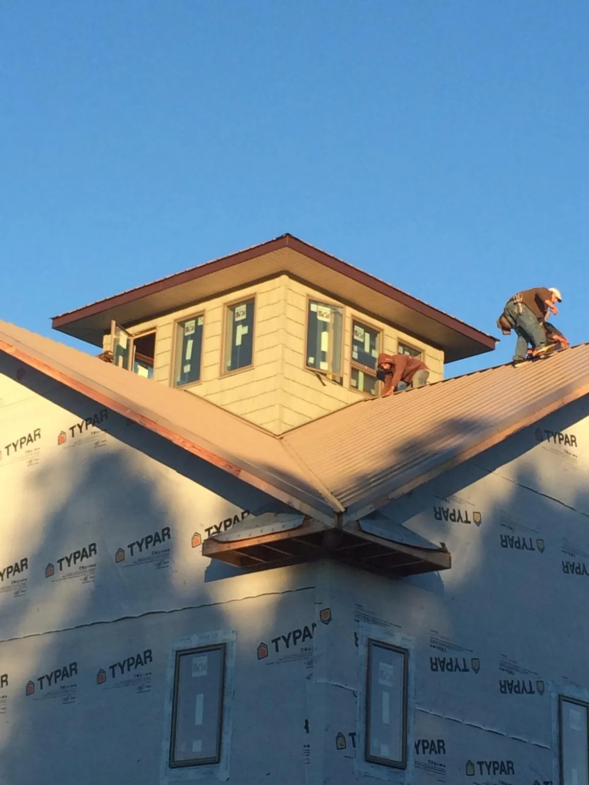 Roofers working around a rooftop cupola on a new metal roof at sunset — Roof Waterproofing in Wapato by Roofing Brothers